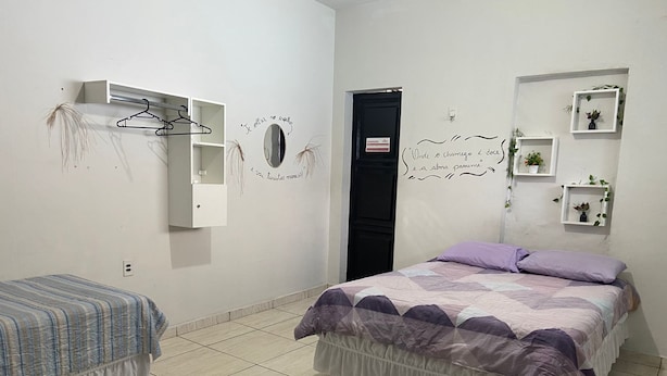 A bedroom with two beds, a wardrobe, a mirror, and wall decorations. - Açaizeiro Hostel (Belém)