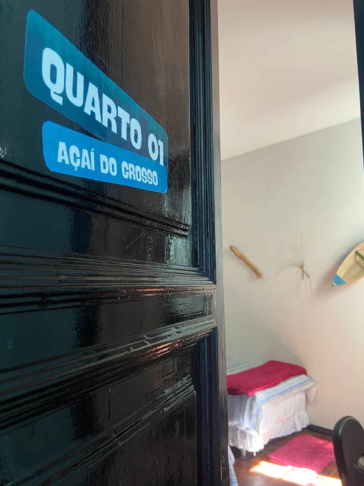 A door with a sign reading 'QUARTO 01' and 'ACAI DO GROSSO'.