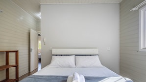 Un dormitorio con una cama, un estante de madera y una ventana.