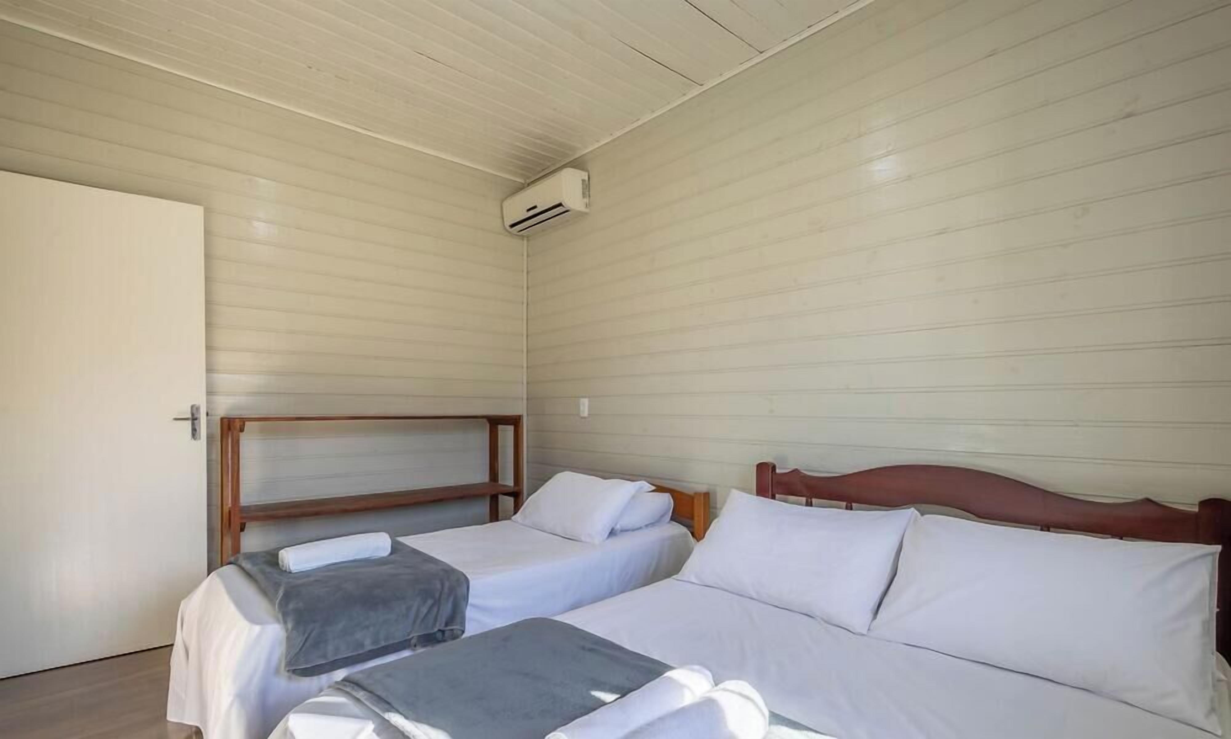 Una habitación con dos camas, cabeceros de madera, ropa de cama blanca y un equipo de aire acondicionado en la pared.