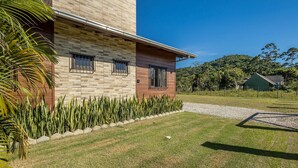 Un edificio moderno con fachada de piedra, césped cuidado y cielo despejado.