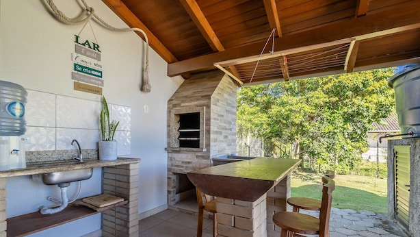 Una cocina rústica al aire libre con encimera de piedra, una lámpara colgante y dispensador de agua.