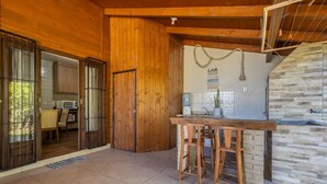 Interior de madera con una zona de cocina que presenta una pared de piedra, una barra de madera y vistas a otra habitación con una ventana.