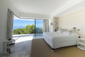 A bedroom with a large bed, a view of the outdoors, and a balcony.