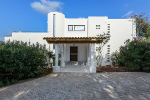 A modern white building with a covered entrance, a small window, and a door.