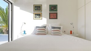 Ett hotellrum med en stor säng, två sänglampor och inramade konstverk på väggen.