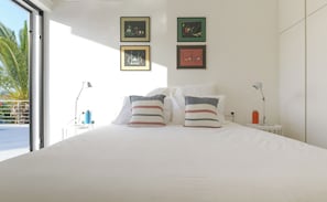 Ein Hotelzimmer mit einem großen Bett, zwei Nachttischlampen und gerahmten Kunstwerken an der Wand.