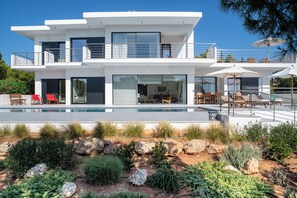A modern two-story house with a swimming pool, outdoor seating, and a well-maintained garden.