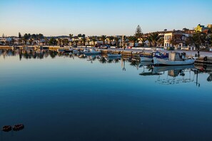 Ein Yachthafen mit vertäuten Booten, ruhigem Wasser und Gebäuden im Hintergrund.