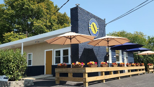 A building with a blue facade, a sign reading 'Nazarath Extended Stay,' and outdoor seating with umbrellas. - Nazareth Extended Stay (Nazareth)