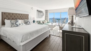 Et moderne hotelværelse med en stor seng, en sofa, et fjernsyn og havudsigt.