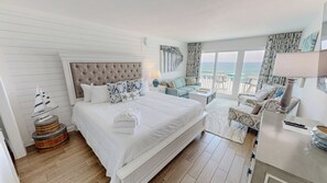 A hotel room with a large bed, a seating area with a view, and a balcony with a table and chairs.