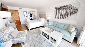 A bedroom with a bed, a blue sofa, a white coffee table, and a patterned rug. - IBR 403 Stunning Beach Front Studio with Free Beach Service for 2 and W/D (Fort Walton Beach)