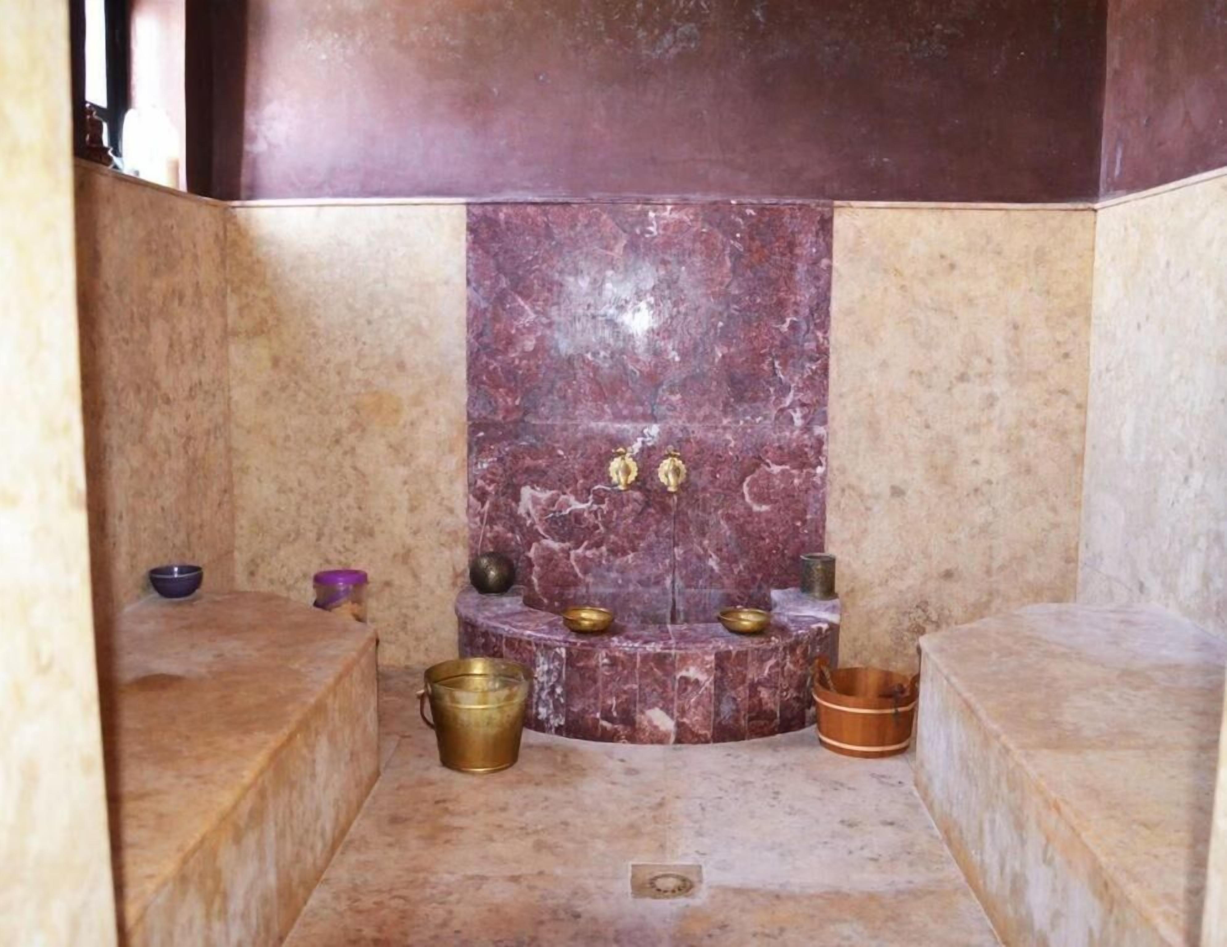Un espacio pequeño y cerrado con un altar de mármol, un cubo de latón y una cuenca de madera.