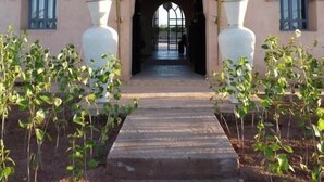 Un bâtiment doté d’une entrée centrale en arc de cercle, flanqué de deux grands vases et de deux fenêtres surmontées d’arcs en ogive.