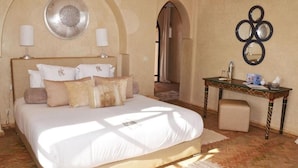 Une chambre à coucher avec un grand lit, deux lampes de chevet, un miroir décoratif et une petite table avec une chaise.