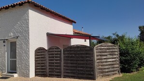Un edifici blanc amb teules vermelles, una porta de fusta i una banca a l'exterior.