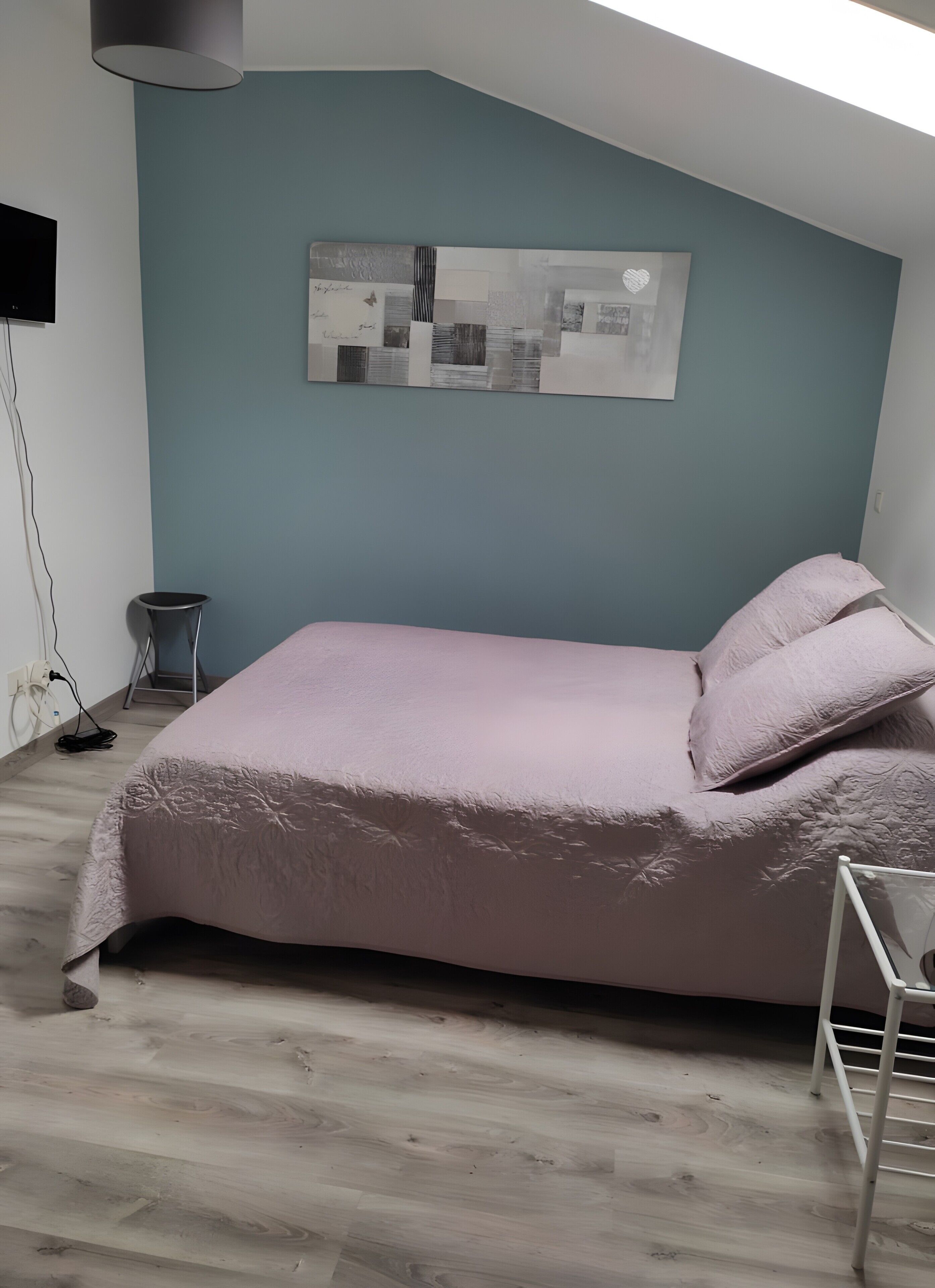 Ein Schlafzimmer mit einem Bett, einer Wanddekoration und einer Deckenleuchte.