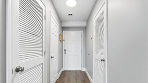 Un couloir étroit avec des portes blanches et un plancher en bois.