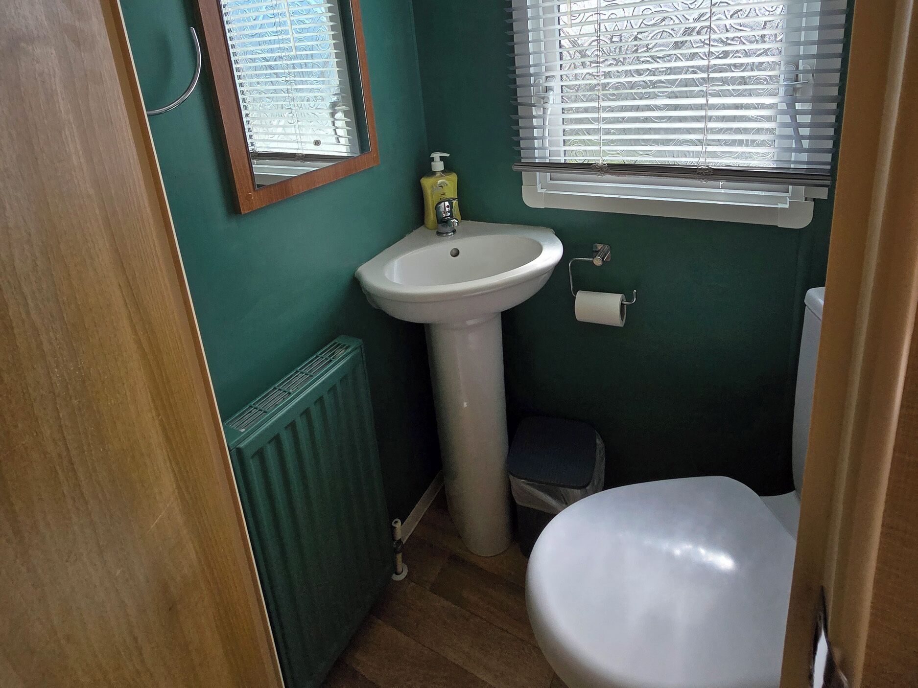 A small bathroom with a white sink, toilet, and radiator.