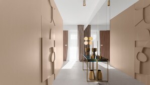 Ein moderner Hotelkorridor mit spiegelndem Boden, einem Glastisch mit Dekoration und einem Spiegel an der Wand.