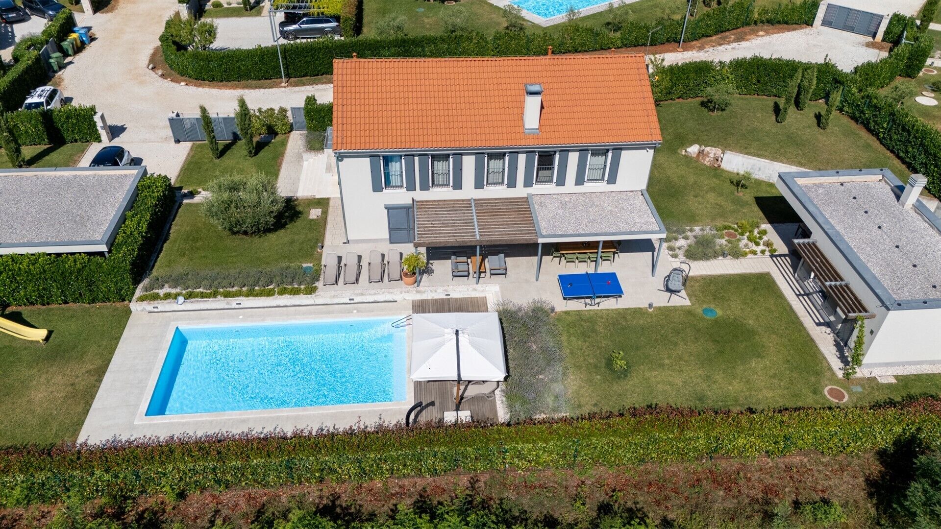 A modern two-story house with a swimming pool, outdoor seating, and a well-maintained garden.