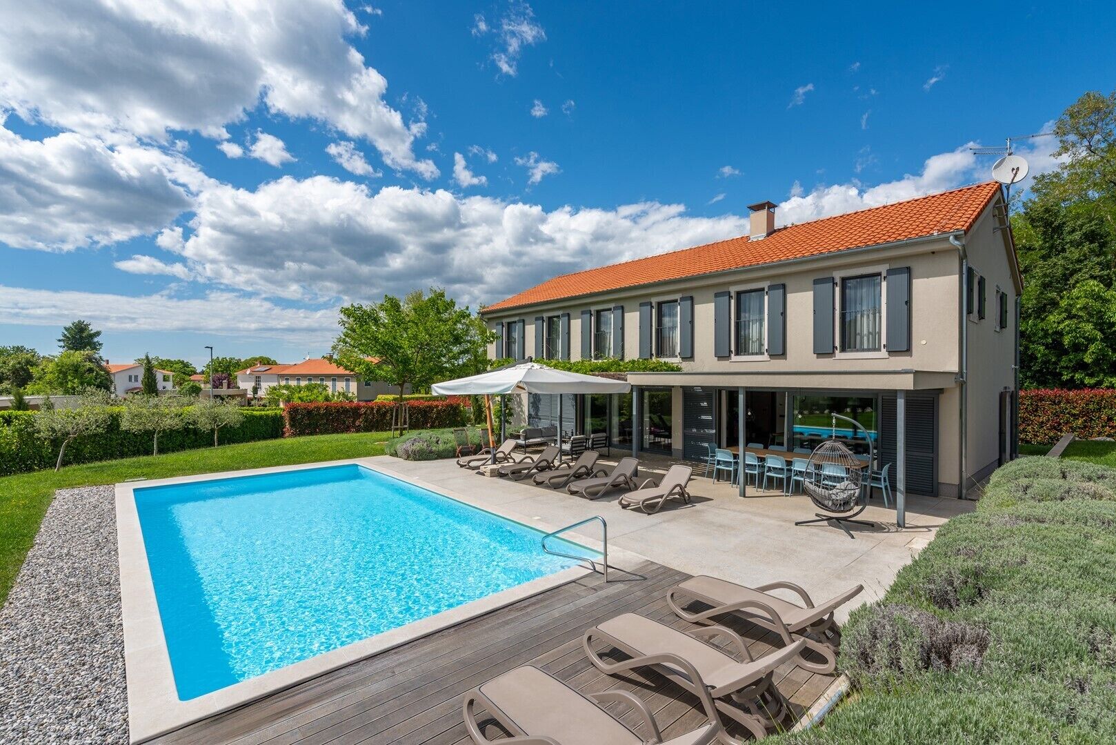 A modern two-story house with a swimming pool, outdoor seating, and a covered patio.
