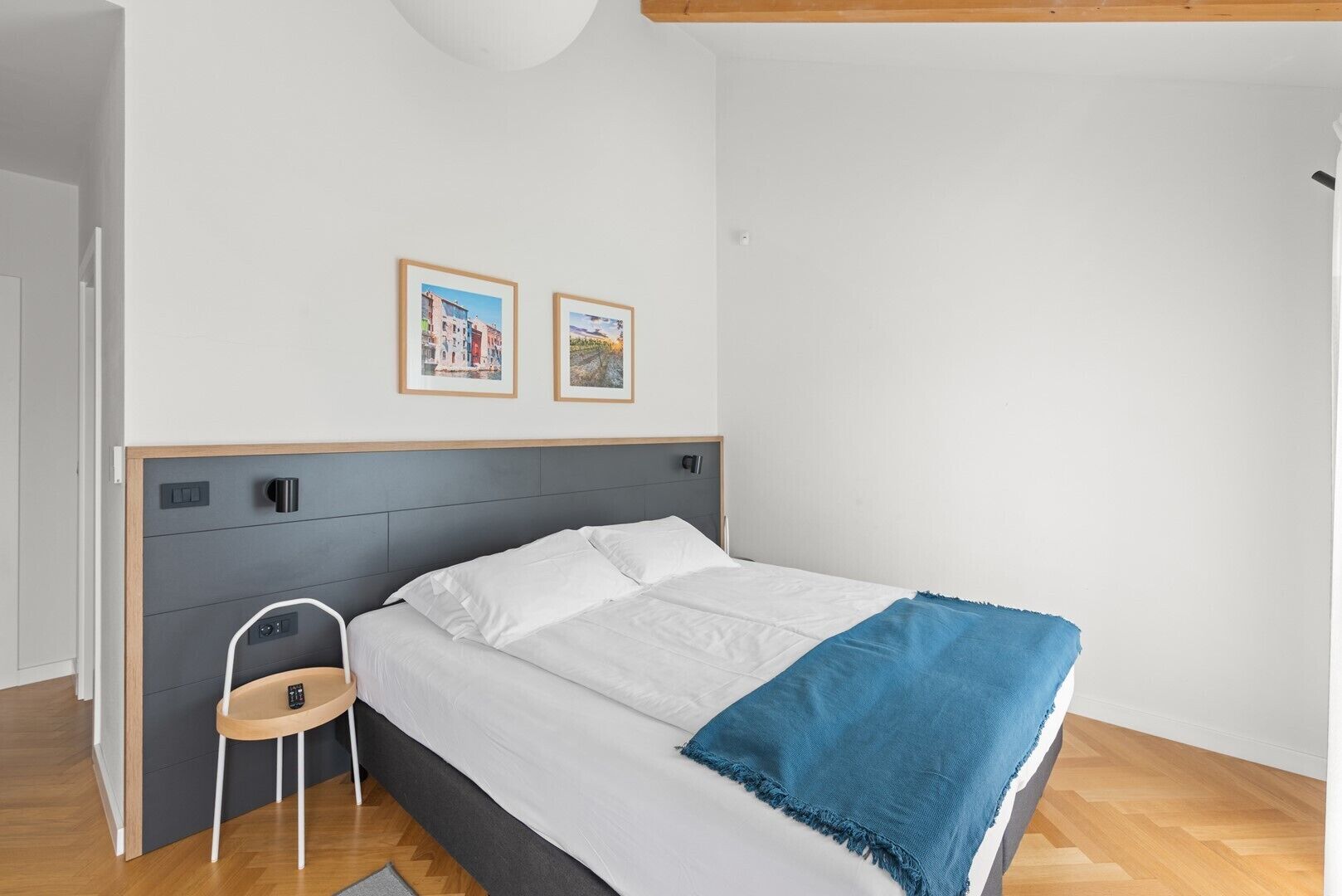 Una camera da letto con un letto, un comodino, una sedia e due quadri appesi al muro.