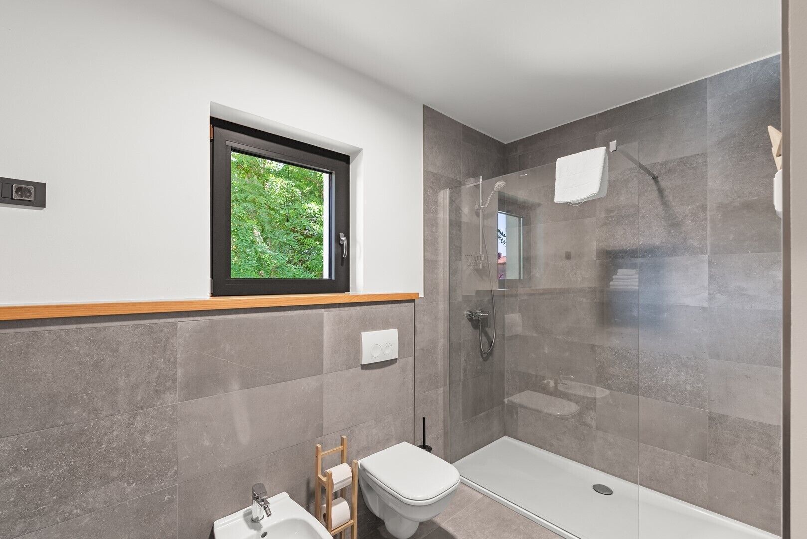 A modern bathroom with a glass-enclosed shower, a toilet, and a sink.