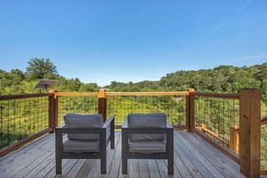 A wooden deck with two chairs facing a wire mesh fence overlooking a forested area. - *Gorgeous 5BD Lodge w/ POOL! Hot Tub + Theater* (Sevierville)