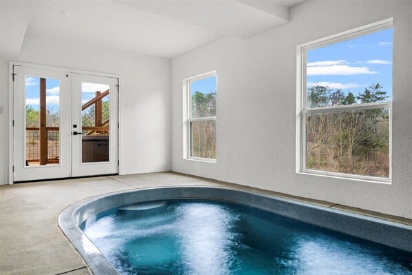 A spa area with a hot tub, large windows, and a view of the outdoors. - *Gorgeous 5BD Lodge w/ POOL! Hot Tub + Theater* (Sevierville)