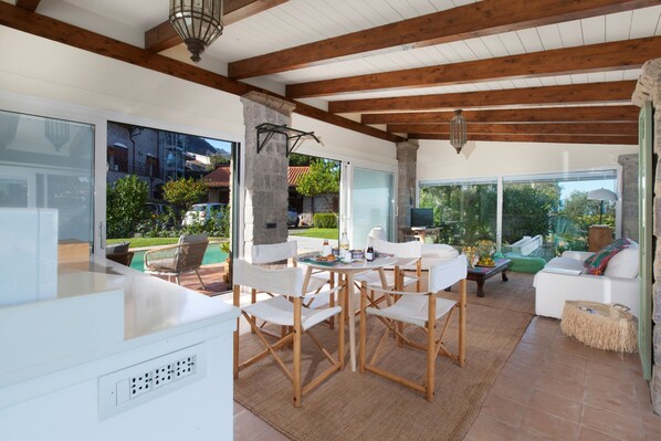 A spacious living area with a wooden ceiling, large windows, and a view of the outdoors. - Villa Florinda in Sorrento (Sorrento)