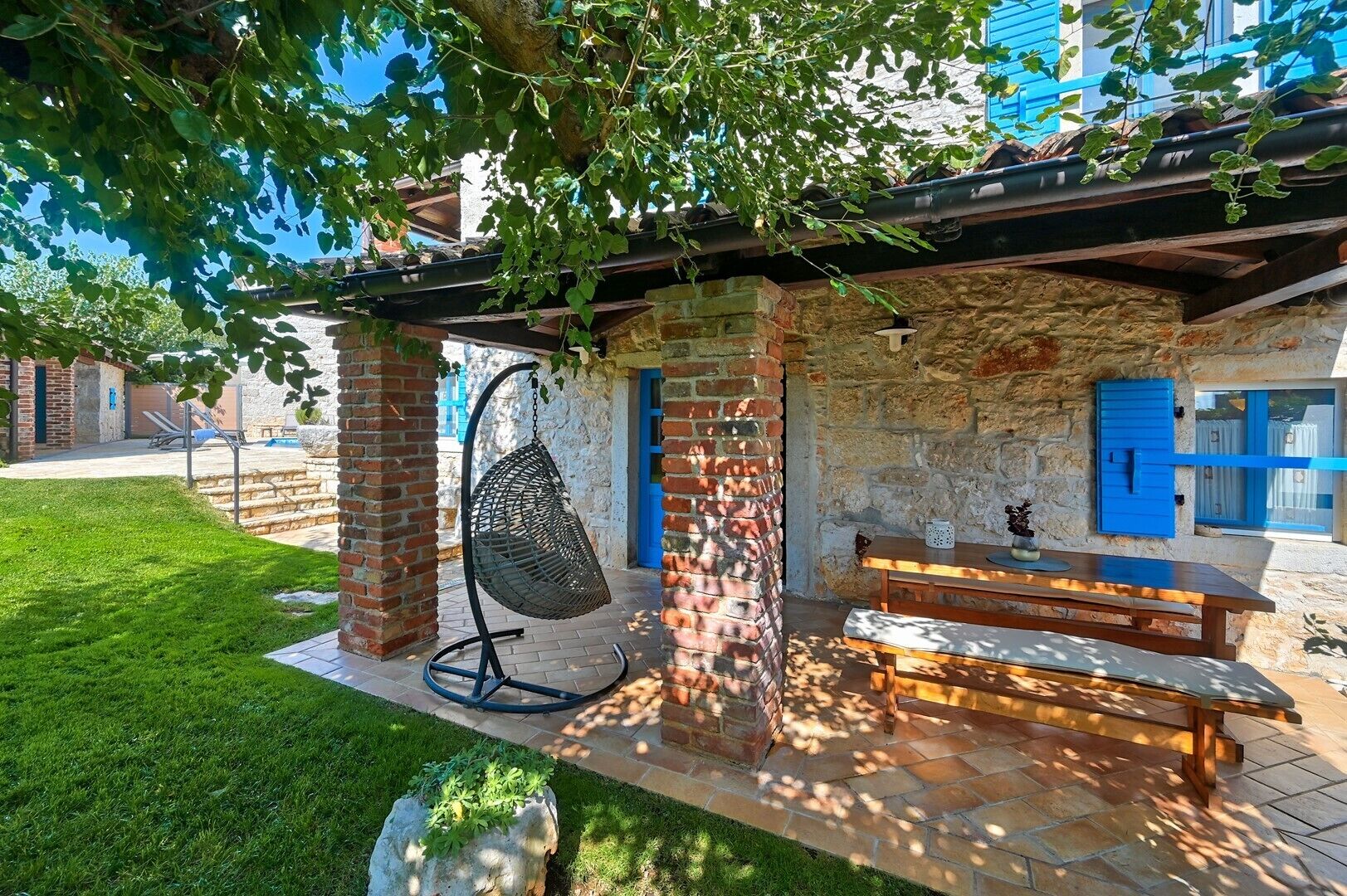 Un patio con una sedia a dondolo, una panca di legno e un muro in pietra.