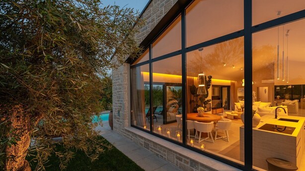 Ein modernes Haus mit großen Glasfenstern, einem Pool und einem hellen Innenraum.