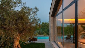 Ein modernes Haus mit Glasfassade, Schwimmbad und gepflegtem Rasen.