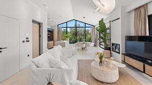 Ein modernes Wohnzimmer mit einer großen Couch, einem Essbereich und einem Fernseher.