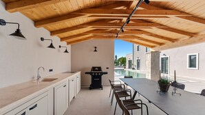 Una cocina moderna con un lavaplatos integrado, una parrilla para barbacoa y un comedor con sillas y una mesa.