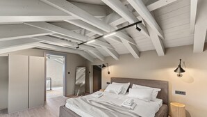 Un dormitorio moderno con una cama grande, vigas de madera en el techo y vistas al exterior.