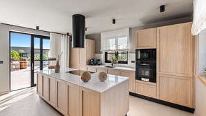 Una cocina moderna con armarios de madera, una isla central y un amplio ventanal.