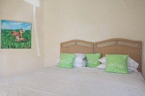 A bedroom with a bed, a headboard, and a painting of a deer in a field. - Luxury beachfront Villa with Chef, and staff (Fitts Village)