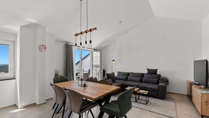 A modern living space with a dining area, a sofa, and a television. - Penthouse Stella Marini for 4+1 guests in Vabriga with Jacuzzi and sea view (Tar)