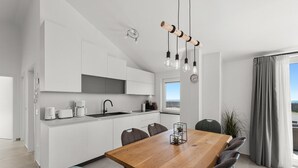 A modern kitchen with white cabinets, a wooden dining table, and a view of the sea through the window. - Penthouse Stella Marini for 4+1 guests in Vabriga with Jacuzzi and sea view (Tar)