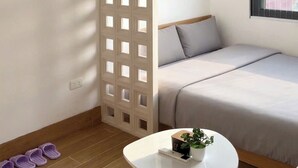 Una habitación moderna con una cama, una mesita con una planta y un separador con aberturas cuadradas.