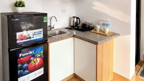Una cocina compacta con armarios de madera, estufa integrada y refrigerador negro.