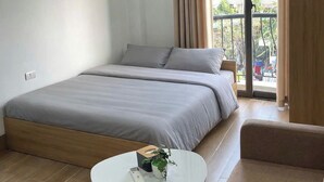 Un dormitorio moderno con una cama grande, una mesita redonda con una planta y un balcón con cortinas.