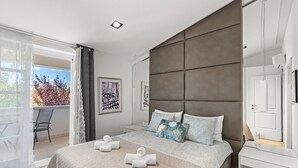 Ein modernes Schlafzimmer mit einem großen Bett, einem Nachttisch, einem Kleiderschrank und einem Balkon mit einem Stuhl.