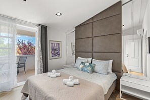 Ein modernes Schlafzimmer mit einem großen Bett, einem Nachttisch, einem Kleiderschrank und einem Balkon mit einem Stuhl.