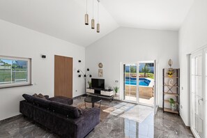 A modern living room with a dark sofa, a flat-screen TV, and a wooden accent wall. - Villa Nina with private pool for 6 guests near Poreč (Bonaci)