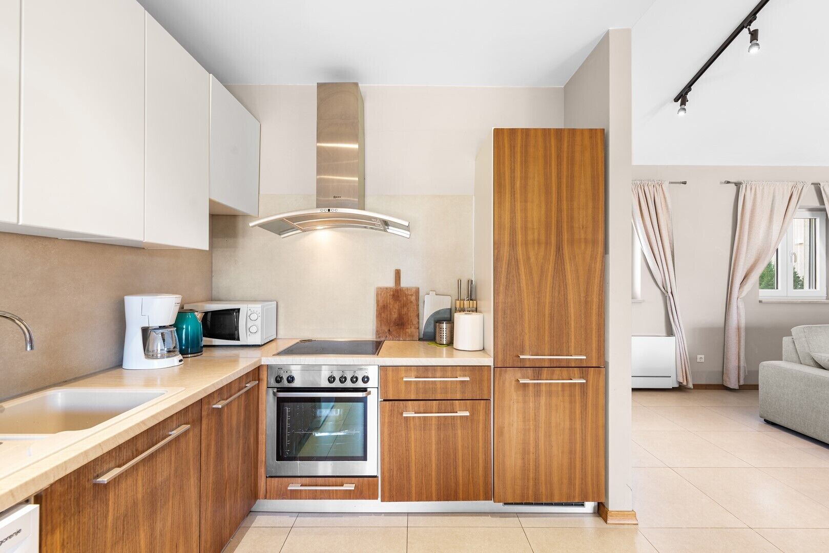 A modern kitchen with wooden cabinets, a built-in oven, a microwave, and a coffee maker.