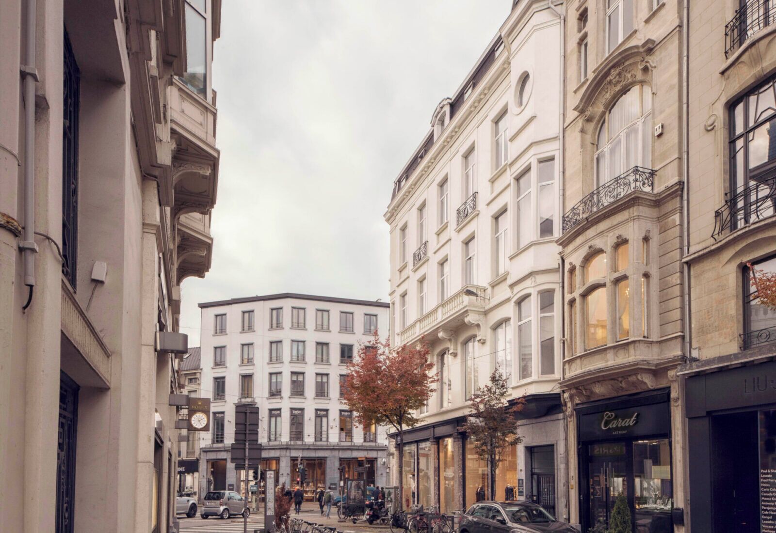 A street view with buildings, a crosswalk, and parked cars.
